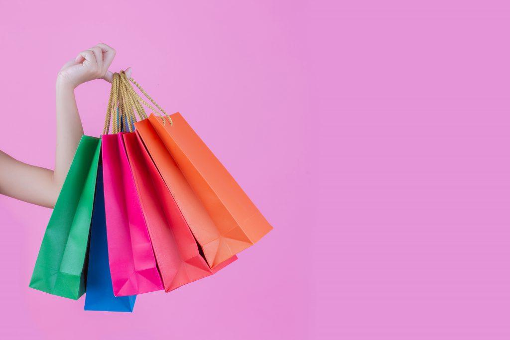 The girl holds a fashion shopping bag and beauty on a pink background.